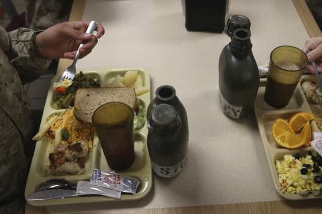 As mandated by their drill instructors, female Marine recruits place their water canteens directly in front of their beverage glass while having lunch during boot camp on February 26, 2013 at MCRD Parris Island, South Carolina. Female enlisted Marines have gone through recruit training at the base since 1949. About 11 percent of female recruits who arrive at the boot camp fail to complete the training, which can be physically and mentally demanding. On January 24, 2013 Secretary of Defense Leon Panetta rescinded an order, which had been in place since 1994, that restricted women from being attached to ground combat units. (Photo by Scott Olson/AFP Photo)