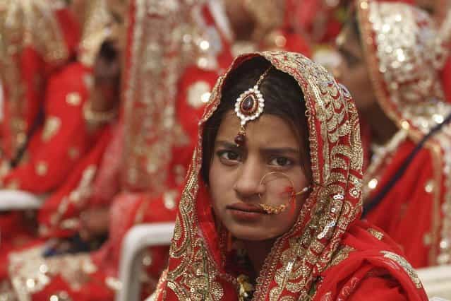 An Indian bride, sits during a mass marriage of 162 Muslim couples in Ahmadabad, India, Sunday, March 3, 2013. Mass marriages in India are organized by social organizations primarily to help the economically backward families who cannot afford the high ceremony costs as well as the customary dowry and expensive gifts that are still prevalent in many communities. (Photo by Ajit Solanki/AP Photo/LaPresse)
