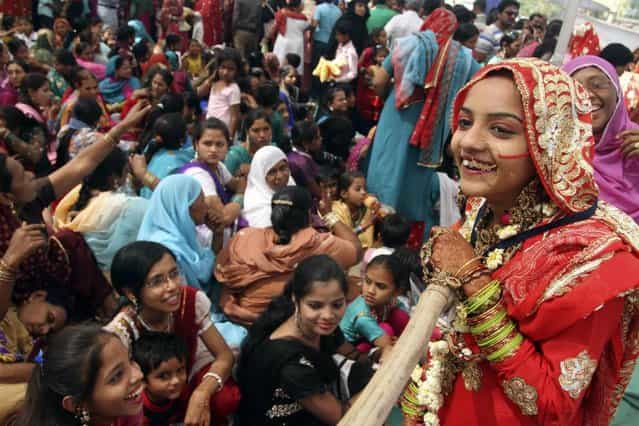 An Indian bride, right, interacts with a relative during a mass marriage of 162 Muslim couples in Ahmadabad, India, Sunday, March 3, 2013. Mass marriages in India are organized by social organizations primarily to help the economically backward families who cannot afford the high ceremony costs as well as the customary dowry and expensive gifts that are still prevalent in many communities. (Photo by Ajit Solanki/AP Photo/LaPresse)