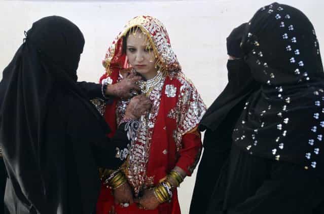 A relative, left, adjusts the costume of a bride during a mass marriage of 162 Muslim couples in Ahmadabad, India, Sunday, March 3, 2013. Mass marriages in India are organized by social organizations primarily to help the economically backward families who cannot afford the high ceremony costs as well as the customary dowry and expensive gifts that are still prevalent in many communities. (Photo by Ajit Solanki/AP Photo/LaPresse)