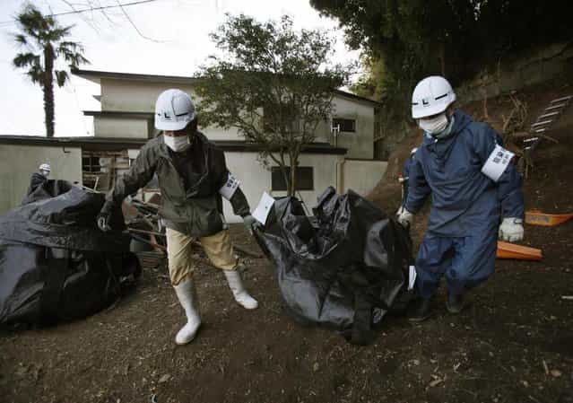 Workers haul a bag of leaves and soil contaminated by radiation, during a clean up operation in the town of Naraha, which was previously inside the exclusion zone surrounding the Fukushima Dai-ichi nuclear plant, in Japan, Wednesday, March 6, 2013. On March 11, Japan marks two years since an earthquake and tsunami caused the plant to spew radiation into the air, contaminating a large area surrounding it. Decontamination operations continue in areas outside the zone, though few residents have returned to the town since it was re-opened. (Photo by Greg Baker/AP Photo)