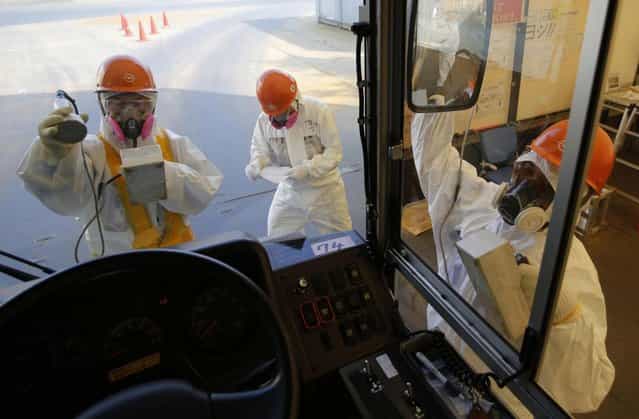 Workers carry out radiation screening on a bus for a media tour at Tokyo Electric Power Co. (TEPCO)'s tsunami-crippled Fukushima Dai-ichi nuclear power plant in Okuma, Fukushima prefecture Wednesday, March 6, 2013, ahead of the second anniversary of the March 11, 2011 tsunami and earthquake. Some 110,000 people living around the nuclear plant were evacuated after the massive March 11, 2011, earthquake and tsunami knocked out the plant's power and cooling systems, causing meltdowns in three reactors and spewing radiation into the surrounding air, soil and water. (Photo by Issei Kato/AP Photo/Pool)