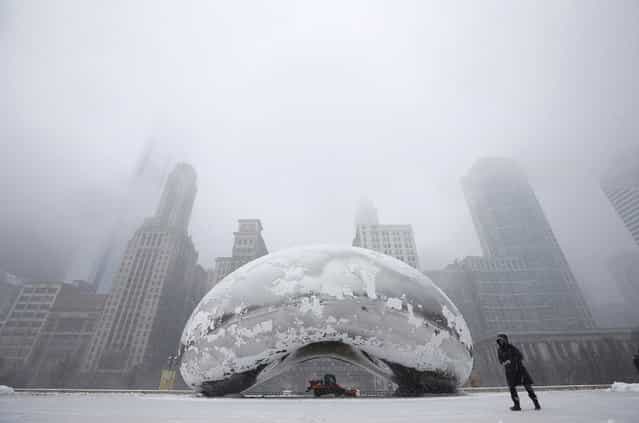 A woman walks by the Cloud Gate Sculpture, known as [The Bean], as a snow plow clears the area during a snowstorm in Chicago March 5, 2013. A deadly late winter storm dumped heavy snow on the Midwestern United States on Tuesday, contributing to numerous highway crashes and flight cancellations as it moved east toward the Ohio Valley and the mid-Atlantic states. (Photo by Jim Young/Reuters)