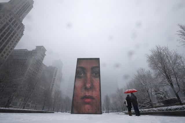 A couple takes pictures of an LED display on 50-ft tall glass towers, projecting images of faces in Crown Plaza during snow in Chicago March 5, 2013. A deadly late winter storm dumped heavy snow on the Midwestern United States on Tuesday, contributing to numerous highway crashes and flight cancellations as it moved east toward the Ohio Valley and the mid-Atlantic states. (Photo by Jim Young/Reuters)