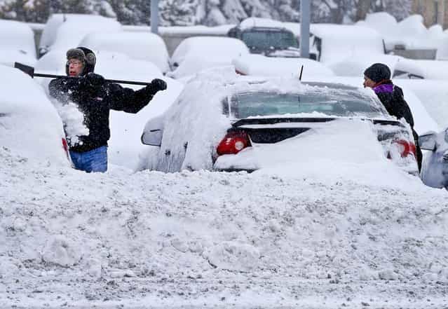 Workers remove snow from cars at an auto dealership in Bloomington, Minnesota, from a storm that is crawling east from the Dakotas and Minnesota toward Chicago which could bring up to 10 inches of snow in some areas, on March 5, 2013. (Photo by Jim Mone/Associated Press)