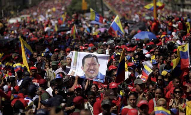 Supporters of Venezuela's late President Hugo Chavez walk behind his coffin as it is paraded through the street as it is moved from the hospital where he died on Tuesday to a military academy in Caracas, on March 6, 2013. (Photo by Rodrigo Abd/Associated Press)