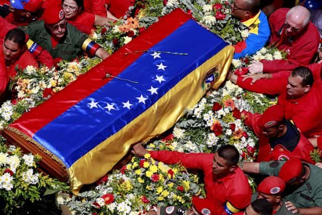The flag-draped coffin containing the body of Venezuela's late President Hugo Chavez is taken to the military academy where it will remain until his funeral, March 6, 2013. Seven days of mourning were declared, all schools were suspended for the week and friendly heads of state were expected for an elaborate funeral Friday. (Photo by Ricardo Mazalan/Associated Press)