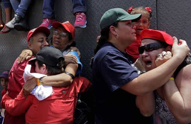 Supporters of Venezuela's late President Hugo Chavez embrace as the coffin containing his body passes in the street, March 6, 2013. (Photo by Rodrigo Abd/Associated Press)