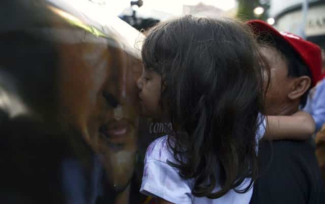 In Caracas, girl kissing photo of Hugo Chavez after the death of the President of Venezuela. (Photo by Juan Barreto/AFP Photo)