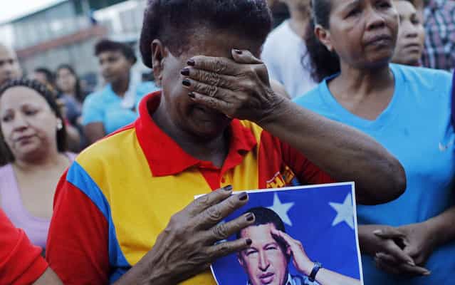 With photo in hand of Hugo Chavez, Venezuela's cries outside the hospital where the president of Venezuela in Caracas was hospitalized when he died on Tuesday. (Photo by Carlos Garcia Rawlins/Reuters)