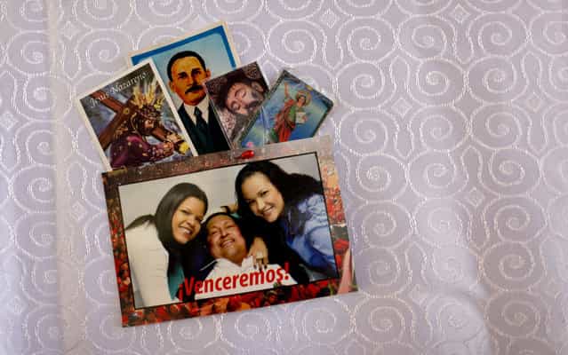 A postcard of Venezuela's President Hugo Chavez with his daughters; Maria Gabriela, left, and Rosa Virginia, is pinned together with prayer cards to the altar cloth in the military hospital's chapel, in Caracas, Venezuela, Tuesday, March 5, 2013. A brief statement read on national television by Communications Minister Ernesto Villegas late Monday carried the sobering news about the charismatic 58-year-old leader's deteriorating health. Villegas said Chavez is suffering from [a new, severe infection]. The state news agency identified it as respiratory. (Photo by Ariana Cubillos/AP Photo)