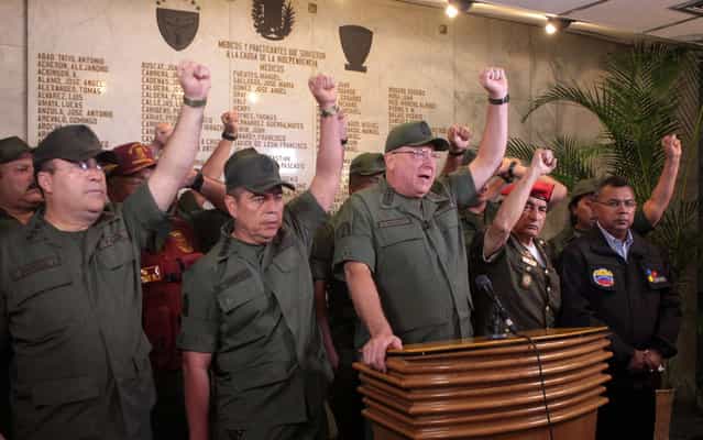 In this photo released by Miraflores Presidential Press Office, Venezuela's Defense Minister Admiral Diego Molero, at the podium, gestures alongside other military leaders during a live televised message to the nation after the vice president announced the death of President Hugo Chavez in Caracas, Venezuela, Tuesday, March 5, 2013. Molero announced that the military will remain loyal to the constitution in the wake of Chavez's death. (Photo by AP Photo/Miraflores Presidential Press Office)
