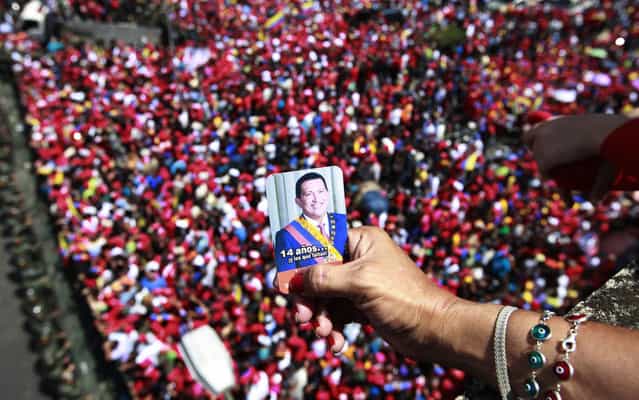 A supporter of Venezuela's late President Hugo Chavez holds a picture of him above a crowd waiting for Chavez's coffin to be taken from the hospital where he died on Tuesday, to a military academy where it will remain until his funeral in Caracas, Venezuela, Wednesday, March 6, 2013. Seven days of mourning were declared, all schools were suspended for the week and friendly heads of state were expected for an elaborate funeral Friday. (Photo by Ricardo Mazalan/AP Photo)