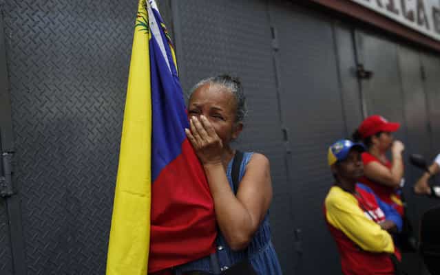A woman holding a Venezuelan flag cries as she watches the coffin containing the body of the late President Hugo Chavez be taken from the hospital, where he died on Tuesday, to a military academy in Caracas, Venezuela, Wednesday, March 6, 2013. Seven days of mourning were declared, all schools were suspended for the week and friendly heads of state were expected for an elaborate funeral on Friday. (Photo by Rodrigo Abd/AP Photo)