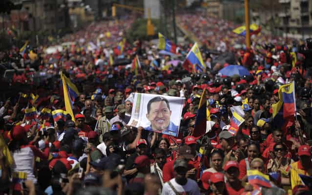 Supporters of Venezuela's late President Hugo Chavez walk behind his coffin as it is paraded through the street as it is moved from the hospital, where he died on Tuesday, to a military academy in Caracas, Venezuela, Wednesday, March 6, 2013. Seven days of mourning were declared, all schools were suspended for the week and friendly heads of state were expected for an elaborate funeral Friday. (Photo by Rodrigo Abd/AP Photo)