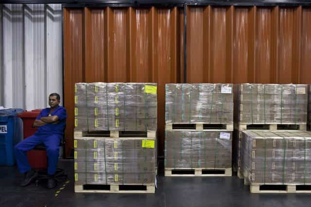 A worker sits next to boxes of Brazilian real coins ready to be shipped at the Casa da Moeda, the national mint, in the Santa Cruz suburb of Rio de Janeiro, Brazil, on Tuesday, March 5, 2013. Brazil is likely to keep its key interest rate at a record low for the third straight meeting, as policy makers are caught between a fragile economic recovery and faster-than-expected inflation. (Photo by Dado Galdieri/Bloomberg)