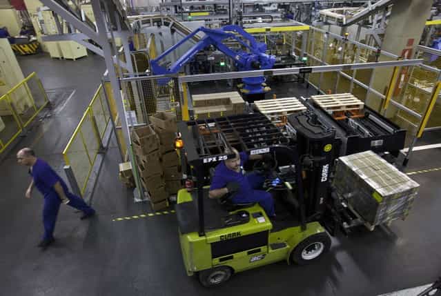 Workers lift boxes of R$ 0.25, or 25 centavos, at the end of the production line at the Casa da Moeda, the national mint, in the Santa Cruz suburb of Rio de Janeiro, Brazil, on Tuesday, March 5, 2013. Brazil is likely to keep its key interest rate at a record low for the third straight meeting, as policy makers are caught between a fragile economic recovery and faster-than-expected inflation. (Photo by Dado Galdieri/Bloomberg)