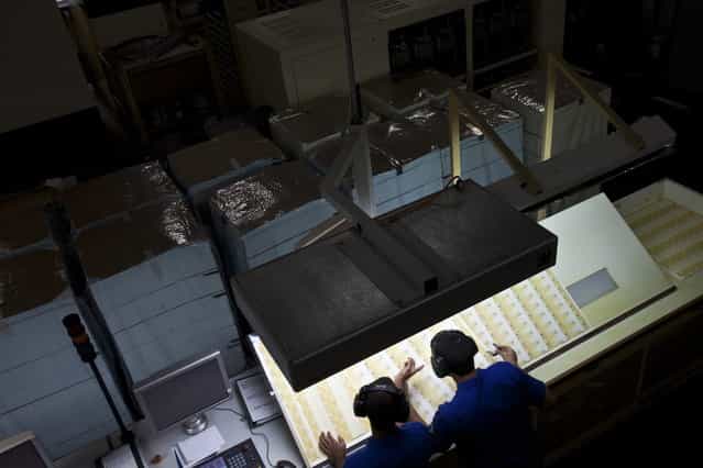 Workers inspect prints of R$ 20 Brazilian reais bills during the production process at the Casa da Moeda, the national mint, in the Santa Cruz suburb of Rio de Janeiro, Brazil, on Tuesday, March 5, 2013. Brazil is likely to keep its key interest rate at a record low for the third straight meeting, as policy makers are caught between a fragile economic recovery and faster-than-expected inflation. (Photo by Dado Galdieri/Bloomberg)