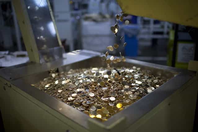 Metal discs fall into a stamping machine to make R$ 0.25 coins, or 25 centavos, at the Casa da Moeda, the national mint, in the Santa Cruz suburb of Rio de Janeiro, Brazil, on Tuesday, March 5, 2013. Brazil is likely to keep its key interest rate at a record low for the third straight meeting, as policy makers are caught between a fragile economic recovery and faster-than-expected inflation. (Photo by Dado Galdieri/Bloomberg)