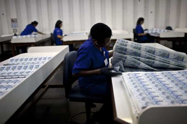Workers check prints of R$ 2 Brazilian reais bills during the production process at the Casa da Moeda, the national mint, in the Santa Cruz suburb of Rio de Janeiro, Brazil, on Tuesday, March 5, 2013. Brazil is likely to keep its key interest rate at a record low for the third straight meeting, as policy makers are caught between a fragile economic recovery and faster-than-expected inflation. (Photo by Dado Galdieri/Bloomberg)