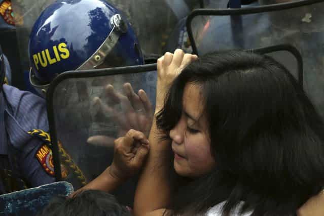 A Filipino protester tries to break through a row of riot police as her group is prevented from marching closer to the U.S. Embassy in Manila to commemorate International Women's Day in the Philippines, on March 8, 2013. Thousands of Filipinos commemorated Women's Day with calls to stop violence against women and children. (Photo by Bullit Marquez/AP Photo)