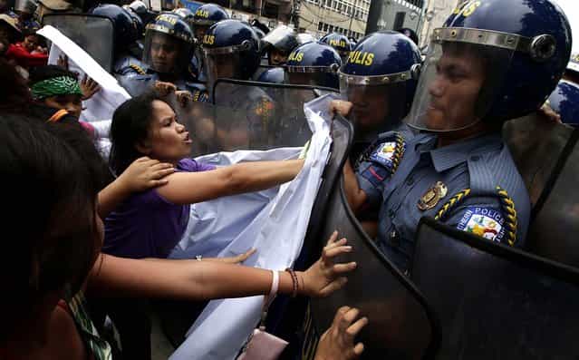 Protesters clash with police as they try to march closer to the US Embassy in Manila to commemorate International Women's Day. Thousands of Filipinos commemorated Women's Day with calls to stop violence against women and children. (Photo by Bullit Marquez/Associated Press)
