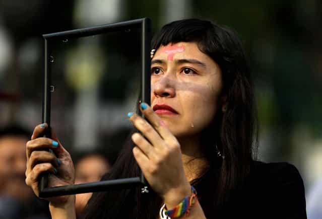 A woman sheds tears as she holds up an empty picture frame during a performance held prior to an International Women's Day march organized by mothers of disappeared daughters, in Ciudad Juarez, Mexico. (Photo by Dario Lopez-Mills/Associated Press)