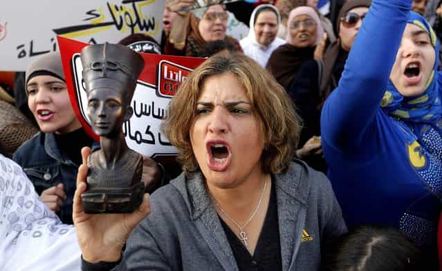 A woman raises a statue of pharaonic Queen Hatshepsut as she shouts slogans during a demonstration in Cairo marking International Women's Day. (Photo by Amr Nabil/Associated Press)