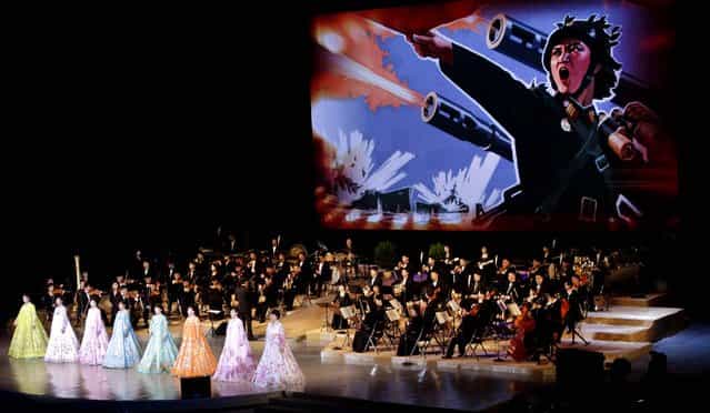An image depicting a female North Korean soldier leading an artillery attack is projected on a large screen behind singers and the Unhasu Orchestra during a concert to mark International Women's Day in Pyongyang, North Korea. (Photo by Jon Chol Jin/Associated Press)