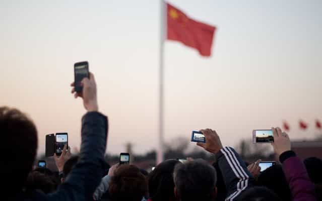 Tourists take photos during the daily flag-lowering ceremony on Tiananmen Square in Beijing on March 4, 2013. Thousands of delegates from across China meet this week to seal a power transfer to new leaders whose first months running the Communist Party have pumped up expectations with a deluge of propaganda. (Photo by Ed Jones/AFP Photo)