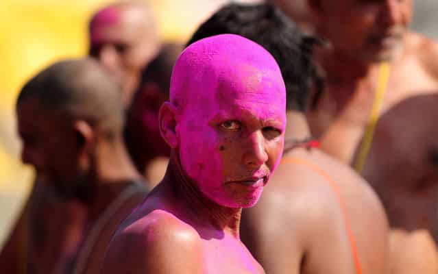 A Bihari Hindu priest, smeared with coloured powder, looks on after the completion of a ritual at the Sangam, the confluence of the rivers Ganges, Yamuna and mythical Saraswati during the Maha Kumbh festival in Allahabad on March 6, 2013. The Kumbh Mela in the town of Allahabad will see up to 100 million worshippers gather over 55 days to take a ritual bath in the holy waters, believed to cleanse sins and bestow blessings. (Photo by Sanjay Kanojia/AFP Photo)