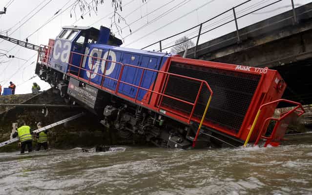 A diesel locomotive has ended up in the river Venoge on March 8, 2013 near Penthalaz, Western Switzerland. The freight locomotive derailed near Cossonez railway station with its driver slightly injured. (Photo by Fabrice Coffrini/AFP Photo)