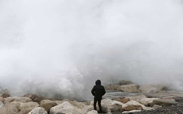 A man looks at waves breaking on the rocks on the beach along the [Promenade des Anglais], on March 6, 2013 in Nice, southeastern France. (Photo by Valery Hache/AFP Photo)