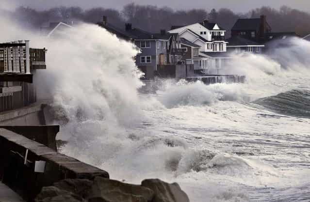 Ocean waves crash over a seawall and into houses along the coast in Scituate, Massachusetts, March 7, 2013. A nor'easter is bringing wind-whipped, wet snow to the state, and coastal flooding is expected in communities still recovering from February's blizzard. (Photo by Steven Senne/Associated Press)