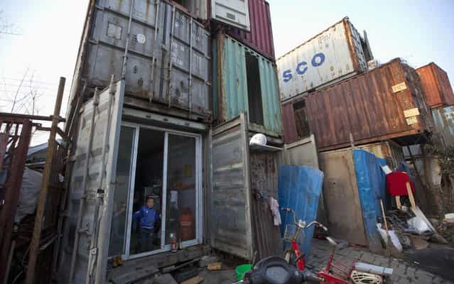 A child stands at the door of a shipping container that serves as his home March 4, 2013 in Shanghai, China. The containers, which house several families, were set up by the landlord, who charges 500 yuans (about 80 dollars) per month for each container. (Photo by Aly Song/Reuters)