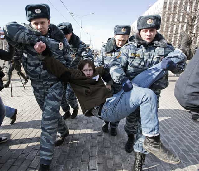Policemen detain an opposition supporter taking part in a picketing calling for the release of two jailed members of the Pussy Riot protest punk band in central Moscow on March 8, 2013. Nadezhda Tolokonnikova, a philosophy student, was sent to prison camp in October 2012 along with bandmate Maria Alyokhina, after being convicted of hooliganism motivated by religious hatred for singing a [punk prayer] in a Moscow cathedral protesting President Vladimir Putin's close links with the Russian Orthodox Church. (Photo by Evgeny Feldman/AFP Photo)