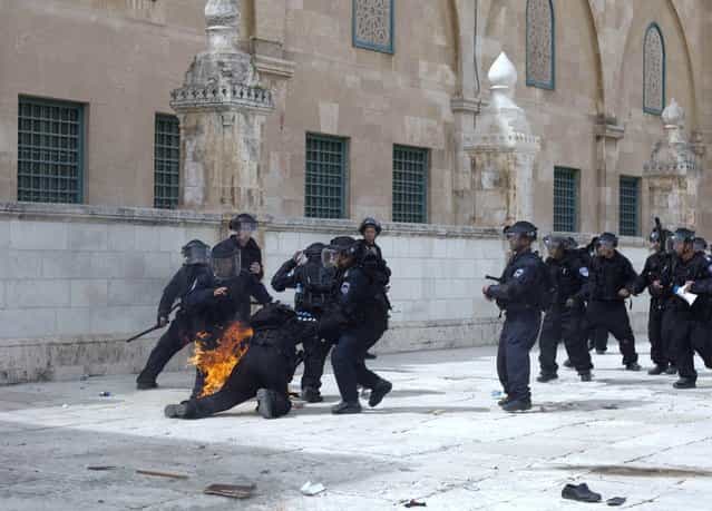 Israeli riot policemen help a comrade after a fire bomb was thrown at him during clashes with Palestinian demonstrators at Jerusalem's al-Aqsa mosque compound following Friday prayers on March 8, 2013. Palestinians enraged by reports that an Israeli policeman mishandled a Koran battled riot officers at Jerusalem's Al-Aqsa mosque compound with stones and petrol bombs, police and witnesses said. (Photo by STR/AFP Photo)