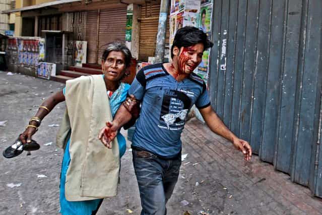 A woman rushes an injured protestor to a safer location after activists clashed with police in Dhaka, Bangladesh, on March 6, 2013.The BNP activists were enrage after police fired protesters during a series of nationwide general strikes this week. (Photo by A.M. Ahad/Associated Press)