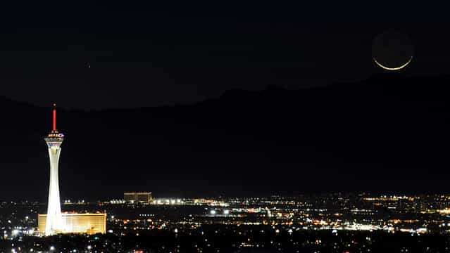The comet PanSTARRS, above and to the right, passes over the Stratosphere Casino Hotel along with a waxing crescent moon over the Spring Mountains range on March 12, 2013 in Las Vegas, Nevada. Officially known as C/2011 L4, the comet got its name after being discovered by astronomers using the Panoramic Survey Telescope & Rapid Response System (Pan-STARRS) telescope in Hawaii in June 2011. (Photo by Ethan Miller)
