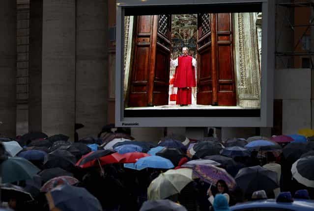 People watch on a video monitor in St. Peter's Square as Monsignor Guido Marini, master of liturgical ceremonies, closes the double doors to the Sistine Chapel in Vatican City at the start of the conclave of cardinals to elect the next pope, on March 12, 2013. Marini closed the doors after shouting [Extra omnes], Latin for [all out], telling everyone but those taking part in the conclave to leave the frescoed hall. He then locked it. (Photo by Michael Sohn/Associated Press)