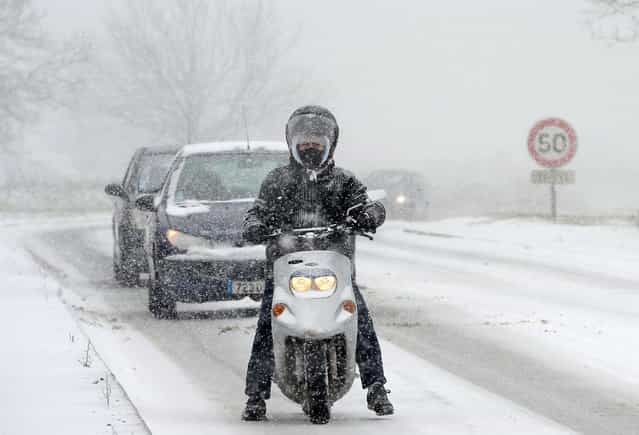 A man rides a scooter on the road N117 around Paris, on March 12, 2013, during a heavy snow storm on France. A heavy late-winter snowstorm hit northwestern Europe on Tuesday, paralysing transport, knocking out power to thousands and leaving hundreds stranded in their cars. (Photo by Franck Fife/AFP Photo)