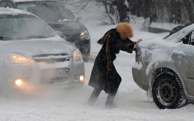 A woman pushes a jammed car as heavy snow falls in Lviv, Ukraine on March 15, 2013. (Photo by Yuriy Dyachyshyn/AFP Photo)