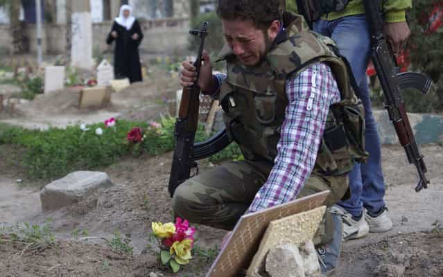 A Free Syrian Army fighter mourns at the grave of his father who was killed by what activists said was shelling by forces loyal to Syria’s President Bashar al-Assad, in a public park that has been converted into a makeshift graveyard in Deir el-Zor, on March 12, 2013. (Photo by Khalil Ashawi/Reuters)