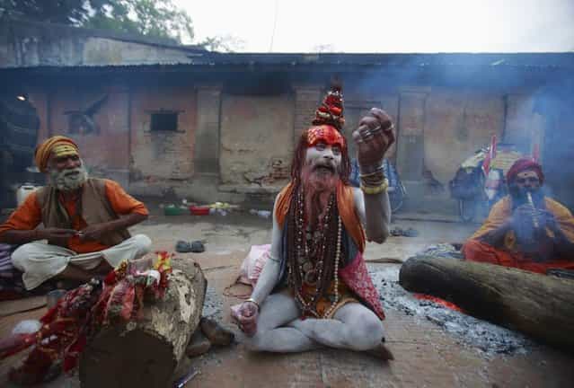 A sadhu (Hindu holy man) asks for money from passing devotees on the premises of Pashupatinath Temple during the Shivaratri festival in Kathmandu March 10, 2013. Celebrated by Hindu devotees all over the world, Shivaratri is dedicated to Lord Shiva, and holy men mark the occasion by praying, smoking marijuana or smearing their bodies with ashes. (Photo by Navesh Chitrakar/Reuters)