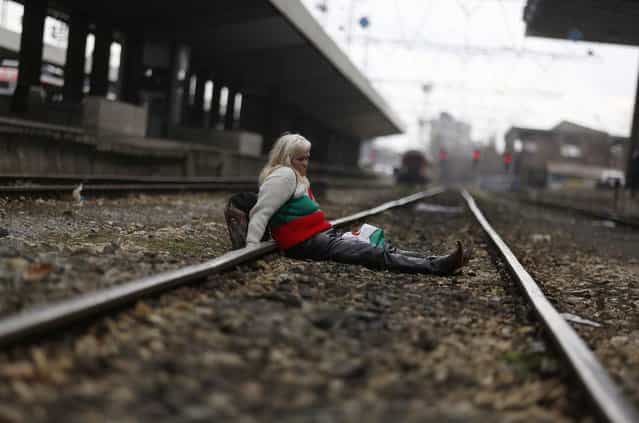 A protester, wearing a sweater in the colours of the Bulgarian national flag, sits on the tracks as demonstrators block the main railway station in Sofia March 10, 2013. Hundreds of Bulgarians took to the streets for a fourth Sunday in a row against monopolies and widespread corruption, demanding a stop to the planned sale of the cargo unit of ailing state railway operator BDZ and an audit of all privatisation deals. (Photo by Stoyan Nenov/Reuters)