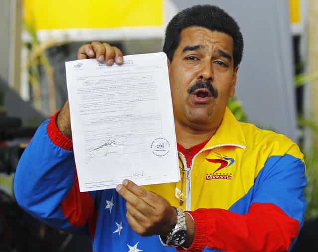 Venezuela's acting President, Nicolas Maduro, shows the document that he signed to register as candidate for president in the April 14th election at the national election board in Caracas March 11, 2013. Presidential candidates Maduro and Henrique Capriles have begun Venezuela's election race with scathing per

<div class=