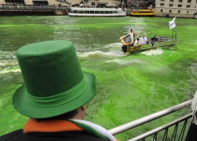 A spectator looks on as the Chicago River is dyed green ahead of the St. Patrick's Day parade in Chicago, Saturday, March, 16, 2013. With the holiday itself falling on a Sunday, many celebrations were scheduled for Saturday because of religious observances. (Photo by Paul Beaty/AP Photo)