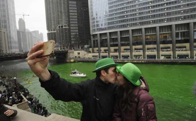 John Shepard and Gena Damento of Rochester Minn., take a photo of themselves kissing after the Chicago River was dyed green ahead of the St. Patrick's Day parade in Chicago, Saturday, March, 16, 2013. With the holiday itself falling on a Sunday, many celebrations were scheduled instead for Saturday because of religious observances. (Photo by Paul Beaty/AP Photo)
