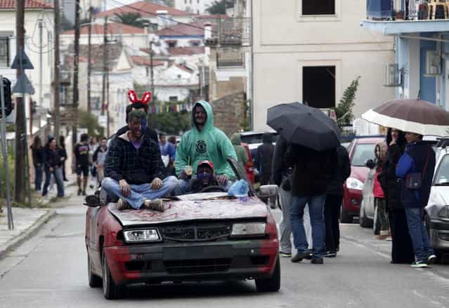 Revellers, atop a makeshift vehicle, celebrate "Ash Monday" by participating in a colourful "flour war", a traditional festivity marking the end of the carnival season and the start of the 40-day Lent period until the Orthodox Easter,in the port town of Galaxidi, some 215 km (134 miles) north west of Athens, March 18, 2013. The revellers "fight" by throwing coloured flour, charcoal dust and powder painting until they essentially run out of supplies. (Photo by Yannis Behrakis/Reuters)
