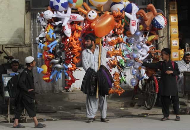 An Afghan man trying to sell balloons attracts Afghan children after school hours in the center of Kandahar, southern Afghanistan, Tuesday, March 19, 2013. (Photo by Allauddin Khan/AP Photo)